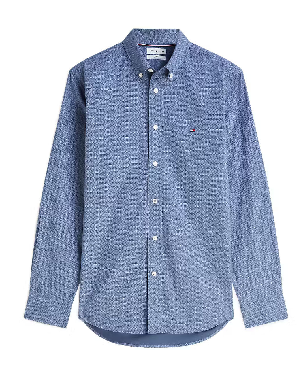 A blue Tommy Hilfiger long-sleeve button-down shirt with a small white geometric pattern, featuring the signature embroidered flag logo on the left chest.